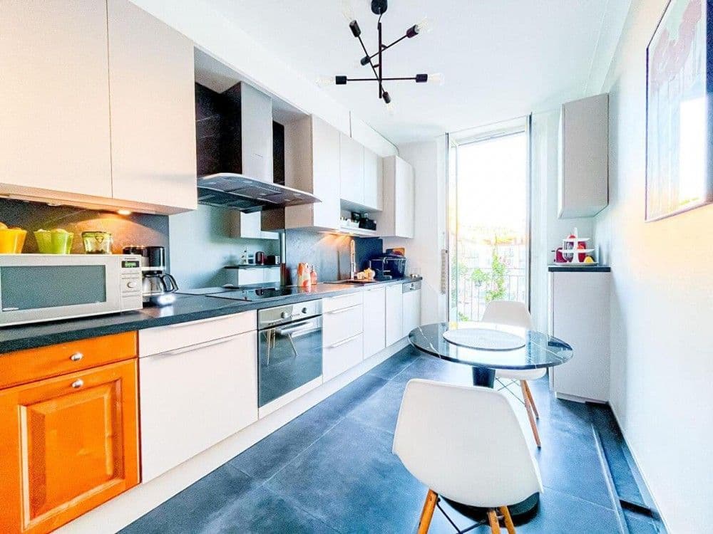 Kitchen with white units, dark worktop and window, 2-bedroom apartment in central Nice