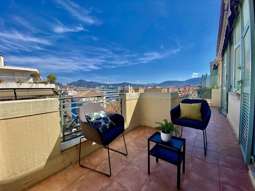 Terrace with armchairs and a view over the rooftops to the hills, 2-bedroom apartment in the Carré d’Or, Nice