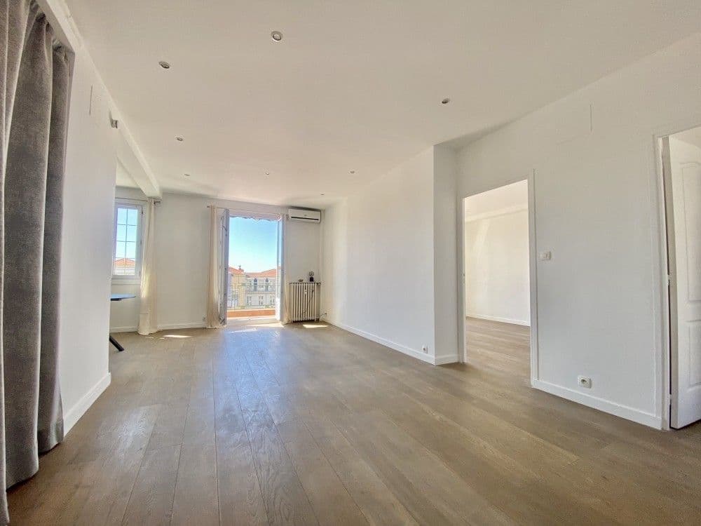 Bright living room with wooden floor and doors to the terrace, 2-bedroom apartment in the Carré d’Or, Nice