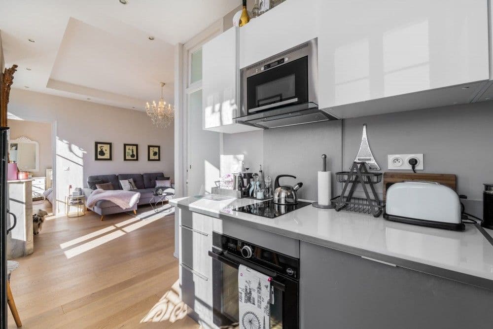 Kitchen with white units and view through to the living room, 2-bedroom apartment in central Nice