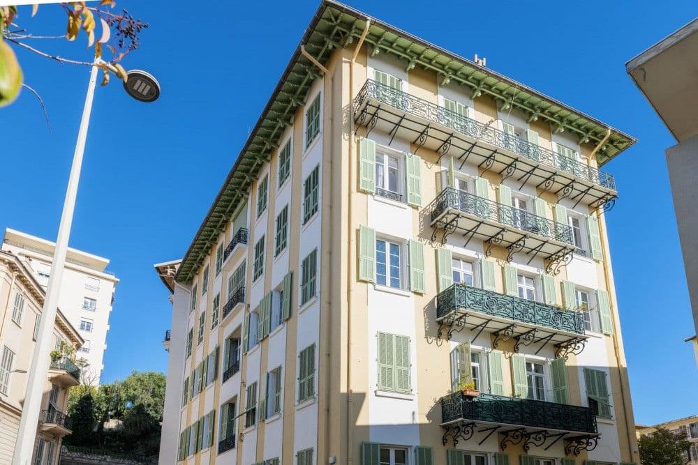 Building façade with green shutters and wrought-iron balconies, 2-bedroom apartment in central Nice