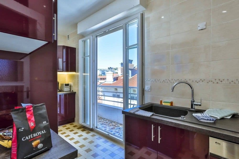 Kitchen with burgundy units and French window, 2-bedroom apartment in the Promenade des Anglais, Nice