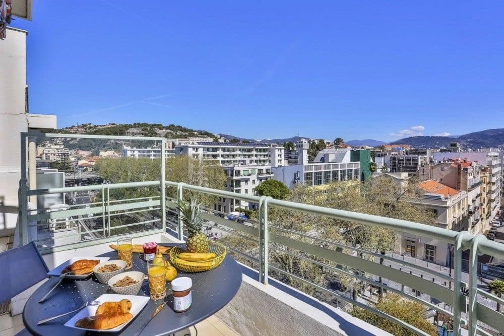 Balcony with breakfast table and a view over the city to the hills, 2-bedroom apartment in the Promenade des Anglais, Nice