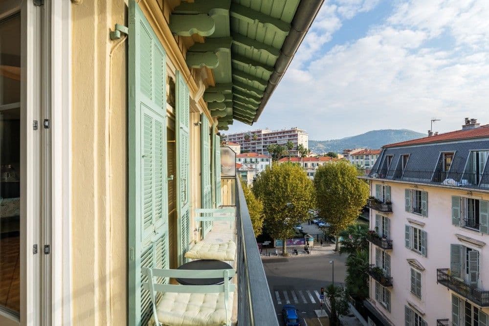 Balcony with green shutters and a view over trees to the hills, 2-bedroom apartment in central Nice