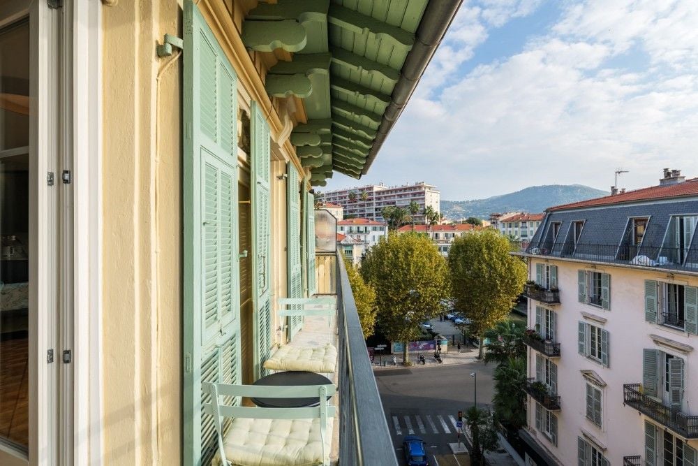 Balcony with green shutters and a view over trees to the hills, 2-bedroom apartment in central Nice