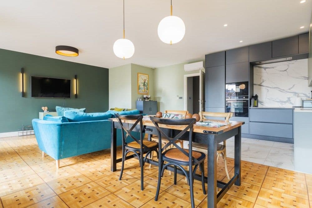 Living room with teal sofa, dining table and open kitchen, 2-bedroom apartment in central Nice