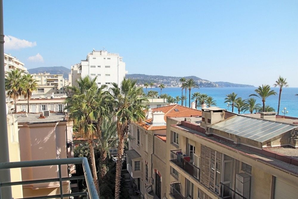 Balcony view over rooftops and palm trees towards the sea, 2-bedroom apartment in the Promenade des Anglais, Nice