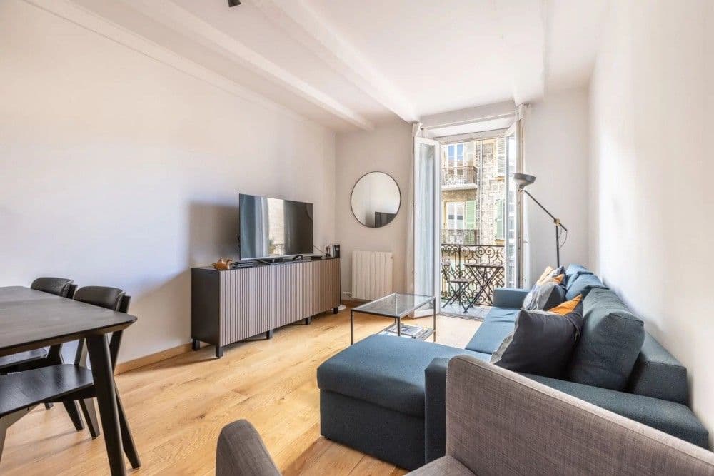 Living room with oak floor, blue sofa and French window to the balcony, 2-bedroom apartment in the Port, Nice