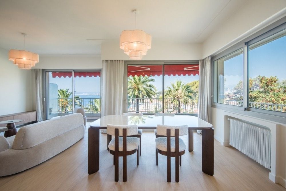 Living and dining room with corner windows and views of palm trees, 2-bedroom apartment in Mont Boron, Nice