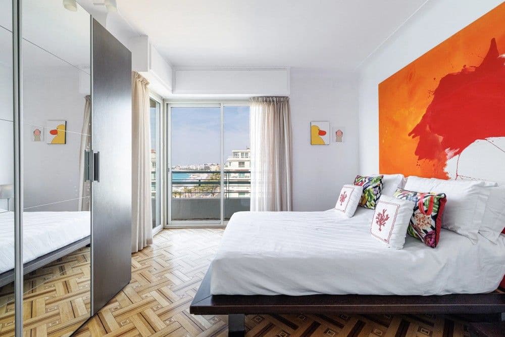 Bedroom with orange artwork and sea-view window, 3-bedroom apartment in the Promenade des Anglais, Nice
