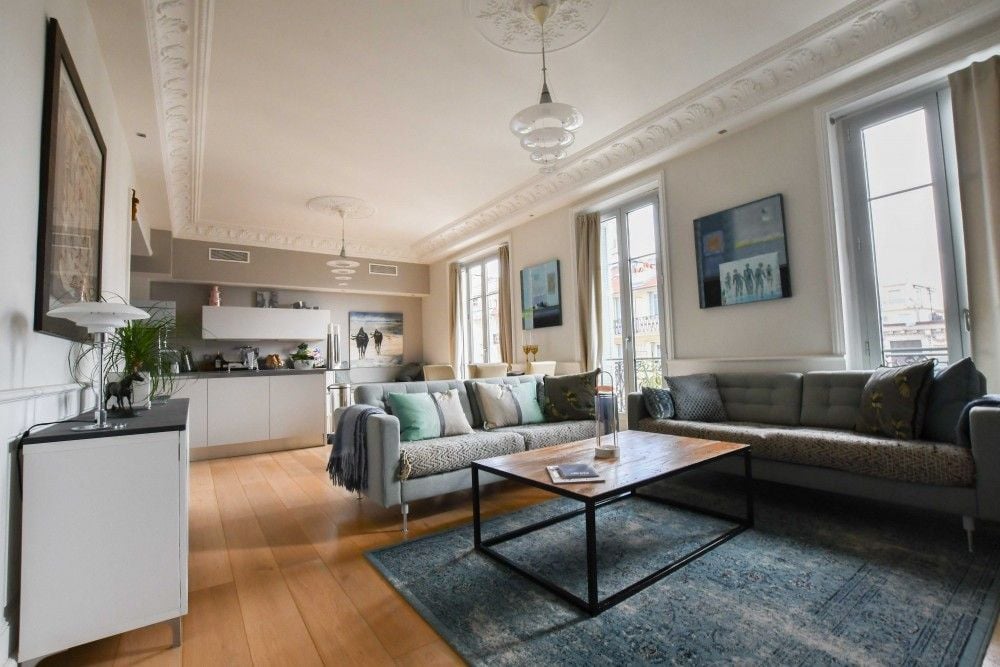 Living room with corner sofa, open kitchen and decorative cornicing, 3-bedroom apartment in the Carré d’Or, Nice