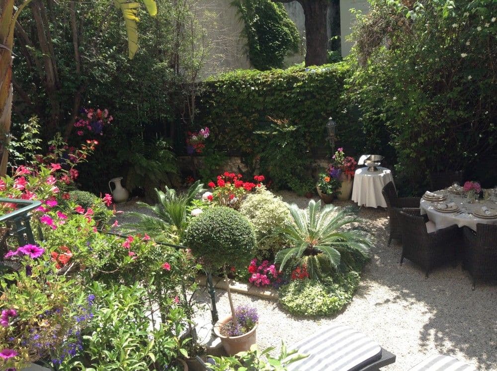 Flowering garden with shrubs and outdoor dining table, 2-bedroom apartment in central Nice