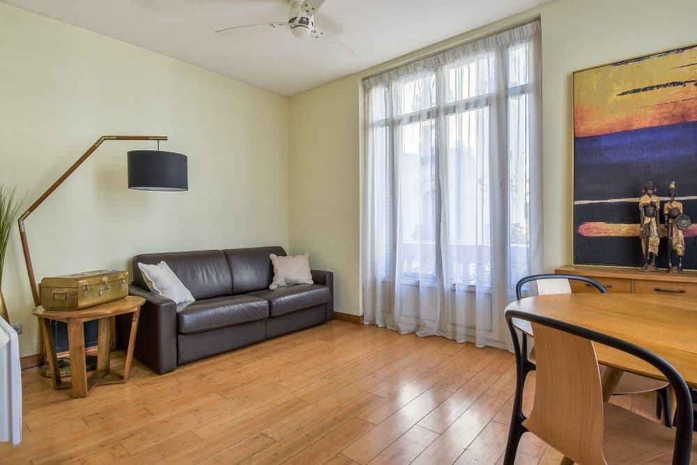 Living room with leather sofa, tall windows and wooden floor, 2-bedroom apartment in the Carré d’Or, Nice