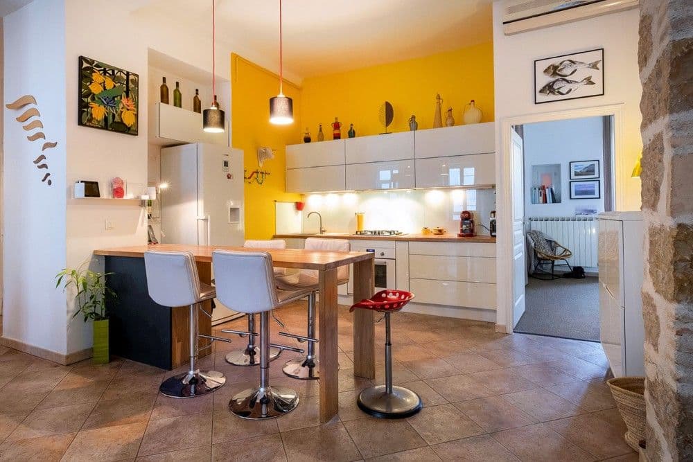 Open-plan kitchen with breakfast bar, bar stools and yellow feature wall, 3-bedroom apartment in the Port, Nice