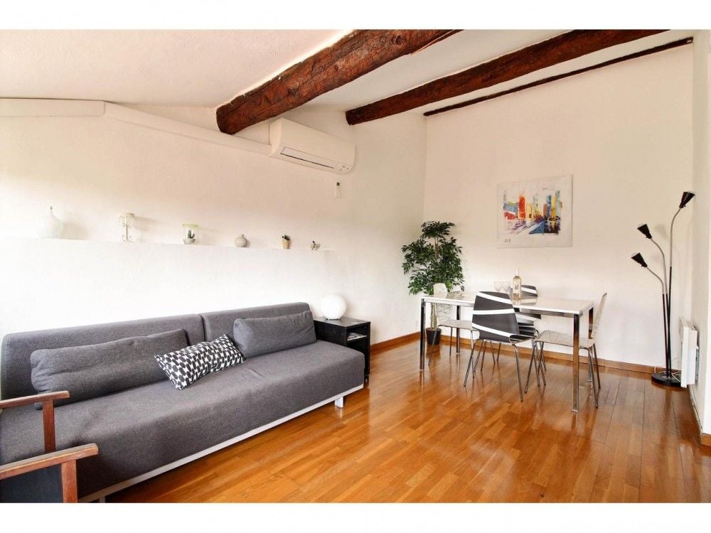 Living room with exposed beams, sofa and dining table, 2-bedroom apartment in the Old Town, Nice