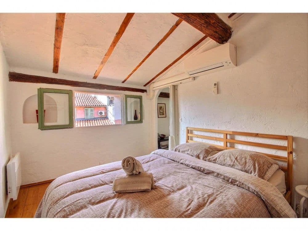 Bedroom with exposed beams and window over the rooftops, 2-bedroom apartment in the Old Town, Nice