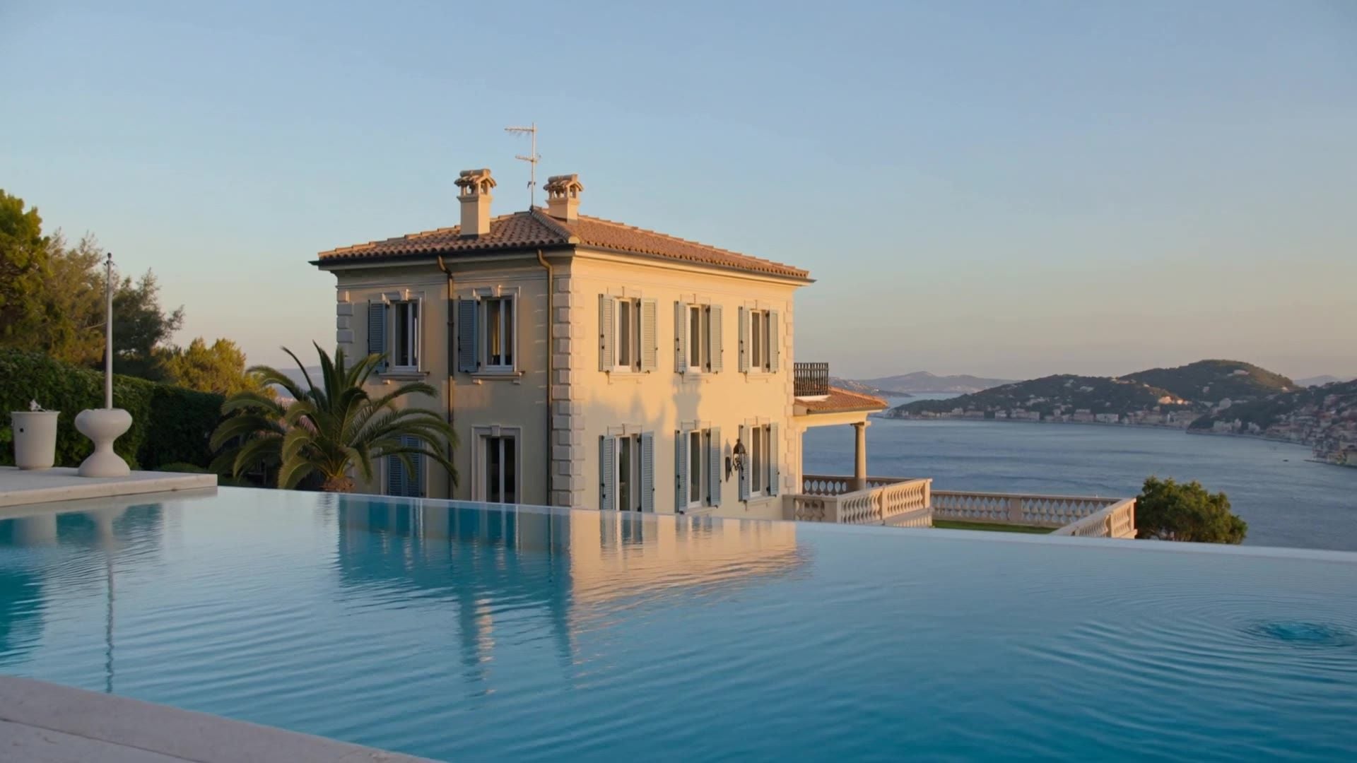 A stone villa by an infinity pool above the sea at sunset