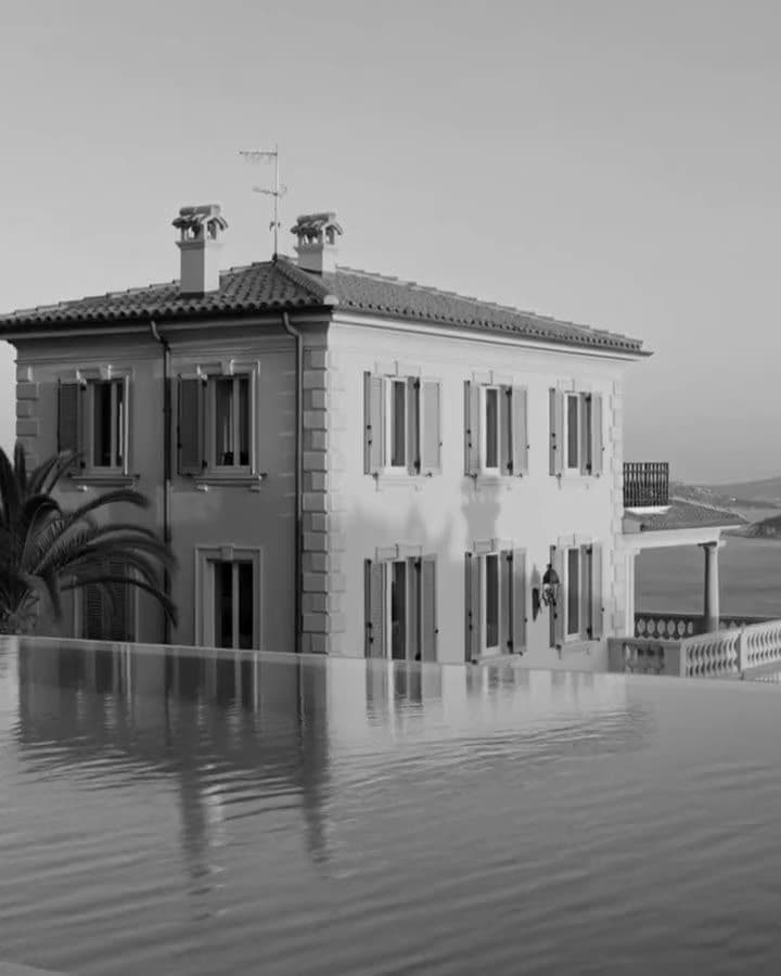 A villa by its pool above the sea, in black and white